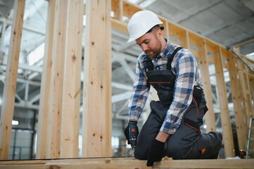 Fototapeta premium Modern modular house. A worker works on the construction of a wooden house