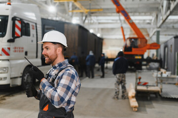 A worker controls the process of loading a modular house onto a truck. Transportation and delivery concept