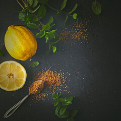Lemon, brown sugar and fresh mint leaves on black stone background. Fresh ingredients for homemade lemonade. Copy space