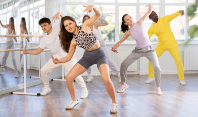 Fototapeta premium Active young woman practicing hip-hop dance in training hall during group dancing classes