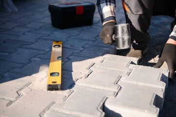 The master in gloves lays paving stones in layers. Garden brick pathway paving by professional...