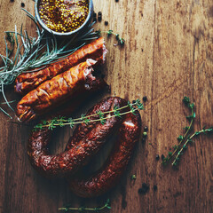 Traditional rustic sausages with herbs on rustic wooden background
