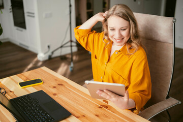 Freelance analyst woman reviewing information on tablet, busy woman working from home office, blond business woman and digital career