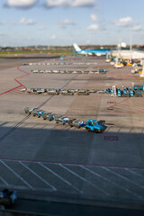 Close-up of airport baggage carts with tilt-shift effect showing miniature-like detail. Aviation ground support operations and logistics.