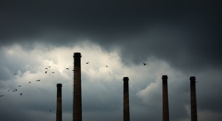 Industrial smokestacks against a stormy sky. Birds fly through the clouds