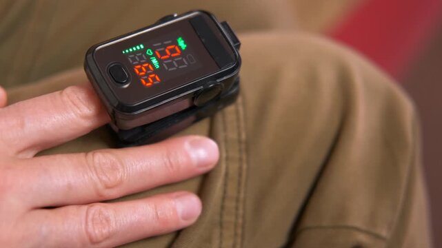 Pulse oximeter measuring blood oxygen saturation and heart rate. Close-up of a pulse oximeter on a person's finger measuring blood oxygen level and heart rate