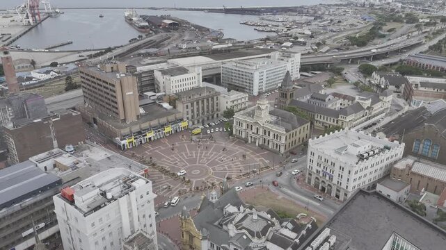 Drone lowers in wide shot of Vuyisile Mini Square with city hall on a cloudy afternoon in Gqeberha, Port Elizabeth, South Africa