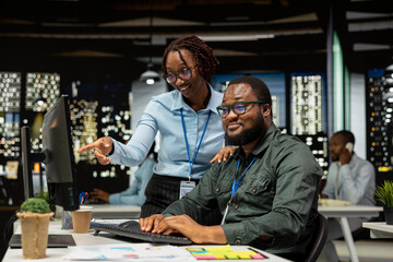 Fototapeta premium African american team of employees working late on goal setting, studying data insights and performance metrics. Colleagues creating reports for business administration, strategy room.