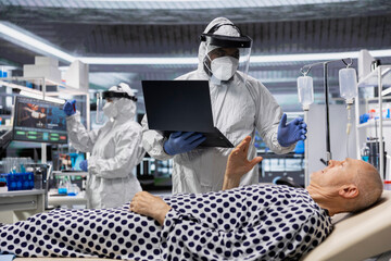 Scientist in protective gear works in biohazard zone to treat a contagious patient, analyzing infection data to advance immunology and epidemic prevention in biotechnology research.