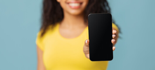 Mockup for application or website. African american woman showing blank mobile phone screen on blue...