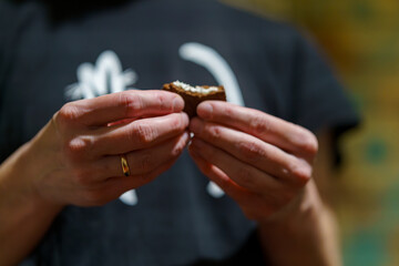 Woman holds a small dessert in his hands before taking a bite in a cozy setting