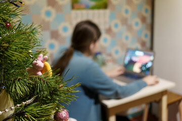 Working at a table with a laptop near a Christmas tree