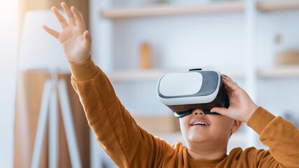 A child is wearing a virtual reality headset and reaching out with one hand. The setting is a living room with simple furniture. Light enters through a window, creating a bright atmosphere.