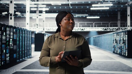 Technician using tablet in data center, integrating new technologies and systems. Employee using device to oversee server hub, ensuring compliance with industry standards, camera A