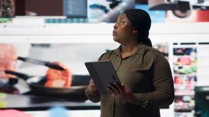 Close up of person using tablet, enjoying leisure time with online video content. Woman browsing social media app on device in front of digital backdrop filled with clips collage layout, camera B