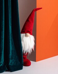 Whimsical scene featuring a gnome with a long red hat and white beard peeking from behind a teal velvet curtain, stands against a retro geometric wall in orange, evoking vintage charm and curiosity.