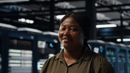 Portrait of cheerful data center engineer conducting security audits to protect against cyber threats. Jolly worker walking in server room, ensuring compliance with industry standards, camera B