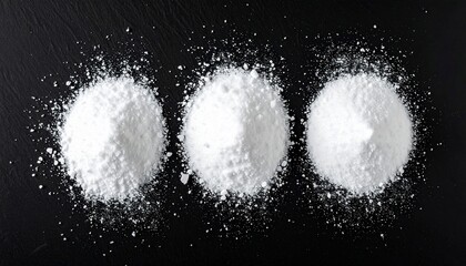 Overhead shot of three white powder piles on black surface, with scattered grains around them
