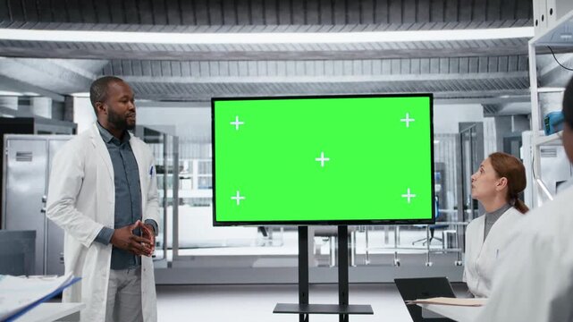 Chroma key display used by lab specialist presenting innovative DNA sequencing project to colleagues. African american man using isolated screen to do briefing for researchers, camera B