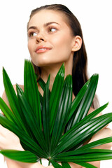 Young woman holding green palm leaves, exuding a natural beauty with a bright smile, perfect for wellness and nature-themed projects.