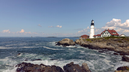 White lighthouse on rocky coastline above ocean waves