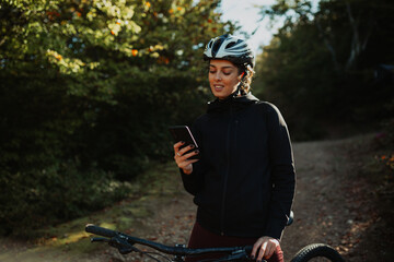 Woman with a helmet using a smartphone for navigation while cycling outdoors
