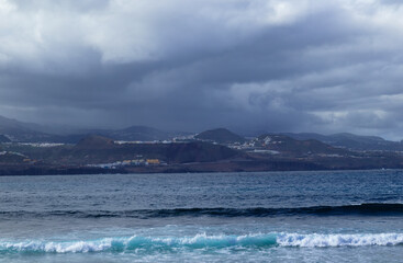 Gran Canaria, view towards the main body of the island from El Confital beach on the edge of Las Palmas de Gran Canaria, rain sweeping through the island
