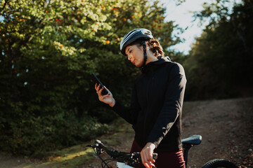 Woman with a helmet using a smartphone for navigation while cycling outdoors