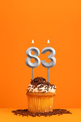 Number 83 candle - Birthday card design in orange background. Cupcake