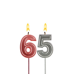 Candle number 65 - Lit birthday candle on white background