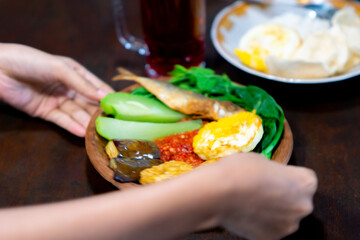 Indonesian spicy (sambal) on an earthenware plate with fried eggplant, fried tempeh, fried salted...