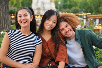 Three cheerful multi ethnic young adult students enjoying their free time together in a park