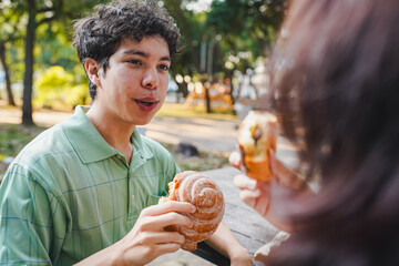 Young man sharing pastry with partner in park