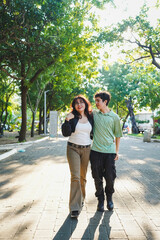 Fototapeta premium Young couple walking together in park enjoying sunny day