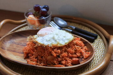 Kimchi fried rice with egg on wooden plate in cozy restaurant, Korean food.
