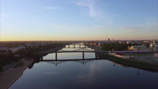 Drone rises over the Volga River in Tver. The camera lifts upward revealing the bridges and city skyline at sunrise.