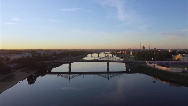 Drone rises over the Volga River in Tver. The camera lifts upward revealing the bridges and city skyline at sunrise.
