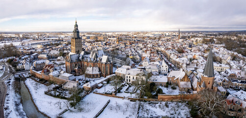 Aerial panorama of Medieval Hanseatic Dutch tower town Zutphen in the Netherlands covered in snow with historic heritage buildings and surrounding Walburgiskerk church. Picturesque painterly landscape