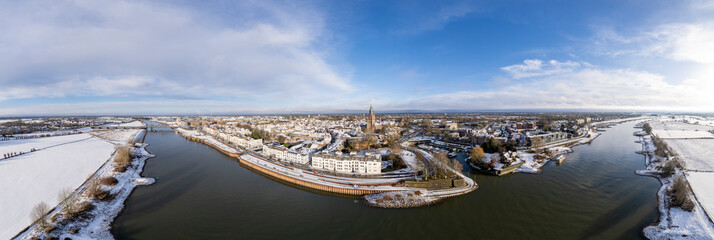 Wide winter wonderland aerial 180 degrees panorama of river IJssel and white floodplains of Dutch Hanseatic medieval tower town Zutphen, The Netherlands. Aerial cityscape after a snowstorm