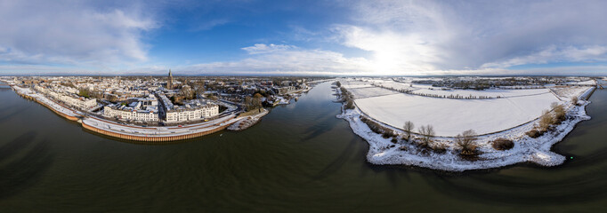 Wide winter wonderland aerial 360 degrees panorama of river IJssel and white floodplains of Dutch Hanseatic medieval tower town Zutphen, The Netherlands. Aerial cityscape after a snowstorm