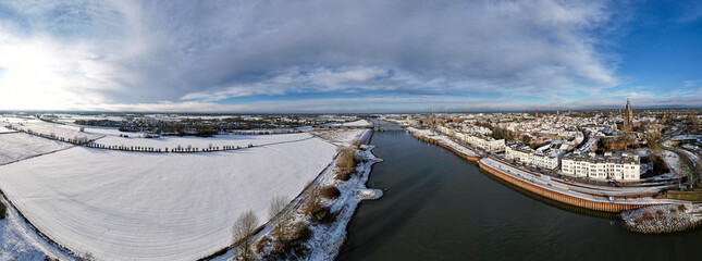 Wide winter wonderland aerial 180 degrees panorama of river IJssel and white floodplains of Dutch Hanseatic medieval tower town Zutphen, The Netherlands. Aerial cityscape after a snowstorm