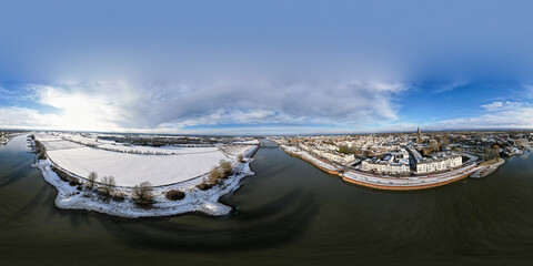 Wide winter wonderland aerial 360 degrees panorama of river IJssel and white floodplains of Dutch Hanseatic medieval tower town Zutphen, The Netherlands. Aerial cityscape after a snowstorm