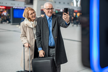 Senior couple taking selfie traveling at airport