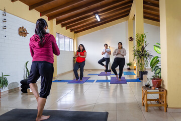 Women practicing yoga tree pose in studio class