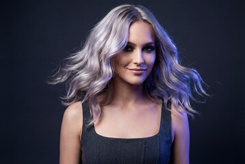 Naklejka premium Beautiful young woman with wavy silver blonde hair smiling confidently on dark blue background