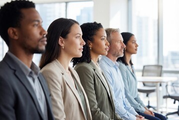 Diverse group of focused business professionals sitting in a row during a corporate presentation