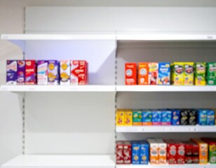 Blurred colorful product boxes on white store shelves