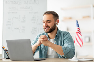 Happy male teacher giving English lesson on web using laptop at home office. Young tutor explaining...