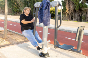 Overweight woman exercising on outdoor gym machine