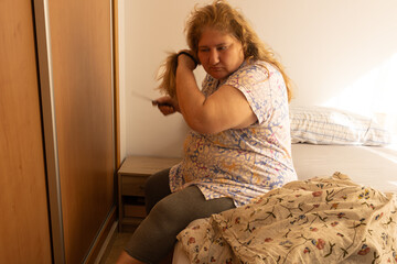 Woman brushing hair in bedroom during morning routine